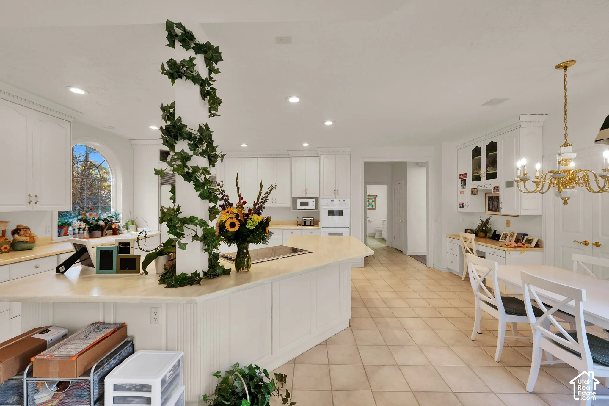 Kitchen featuring white cabinetry, solid-surface countertops, tile flooring, recessed lighting, and a built-in cooktop island