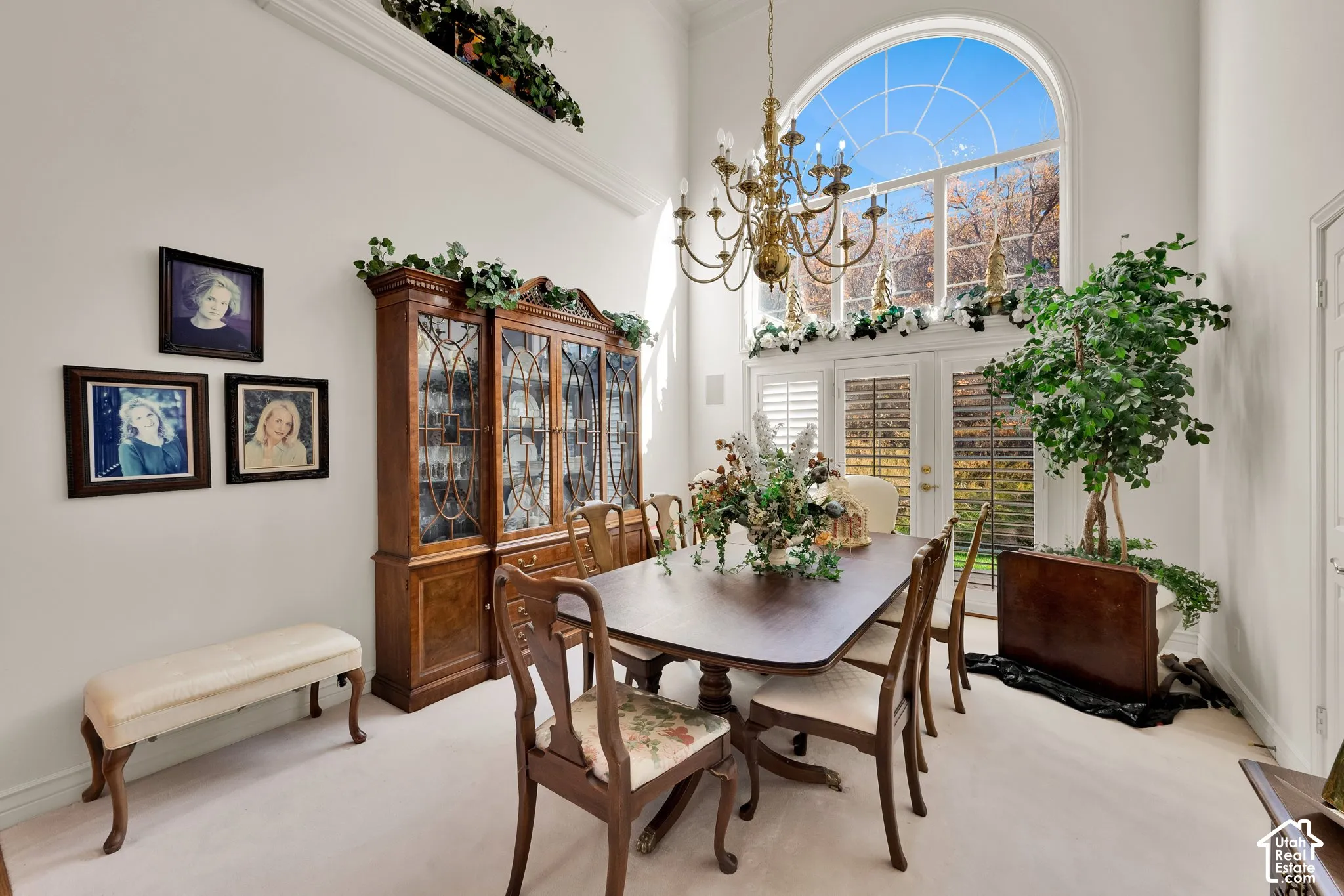 High-ceiling interior featuring a multi-pane arched window, ornate metal chandelier, and double glass-paned doors