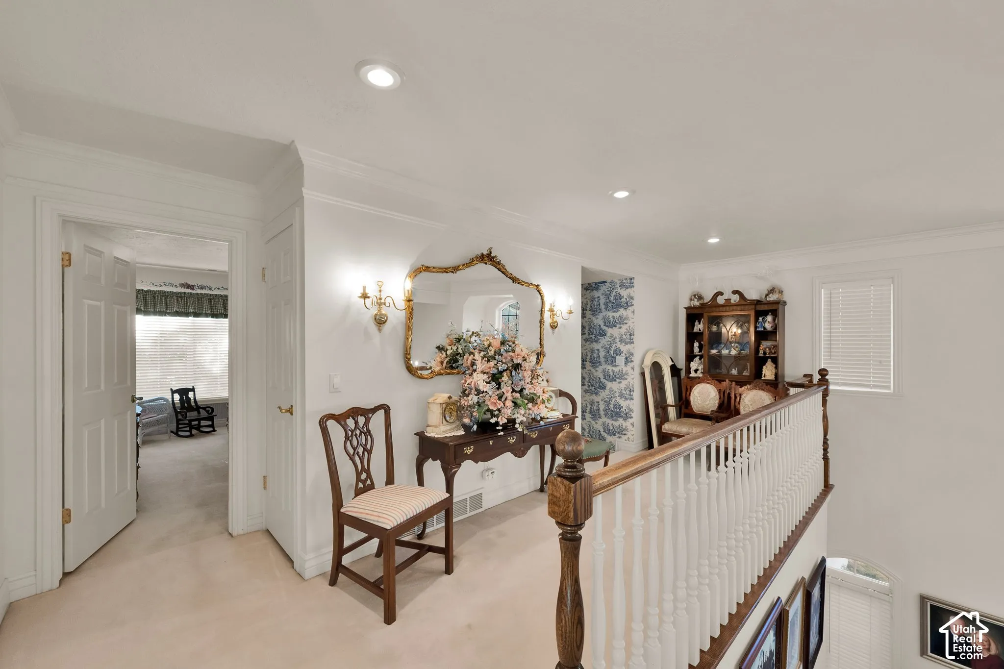 Upper landing featuring a wooden banister with white spindle railing, recessed ceiling lighting, crown molding, and neutral wall-to-wall carpeting