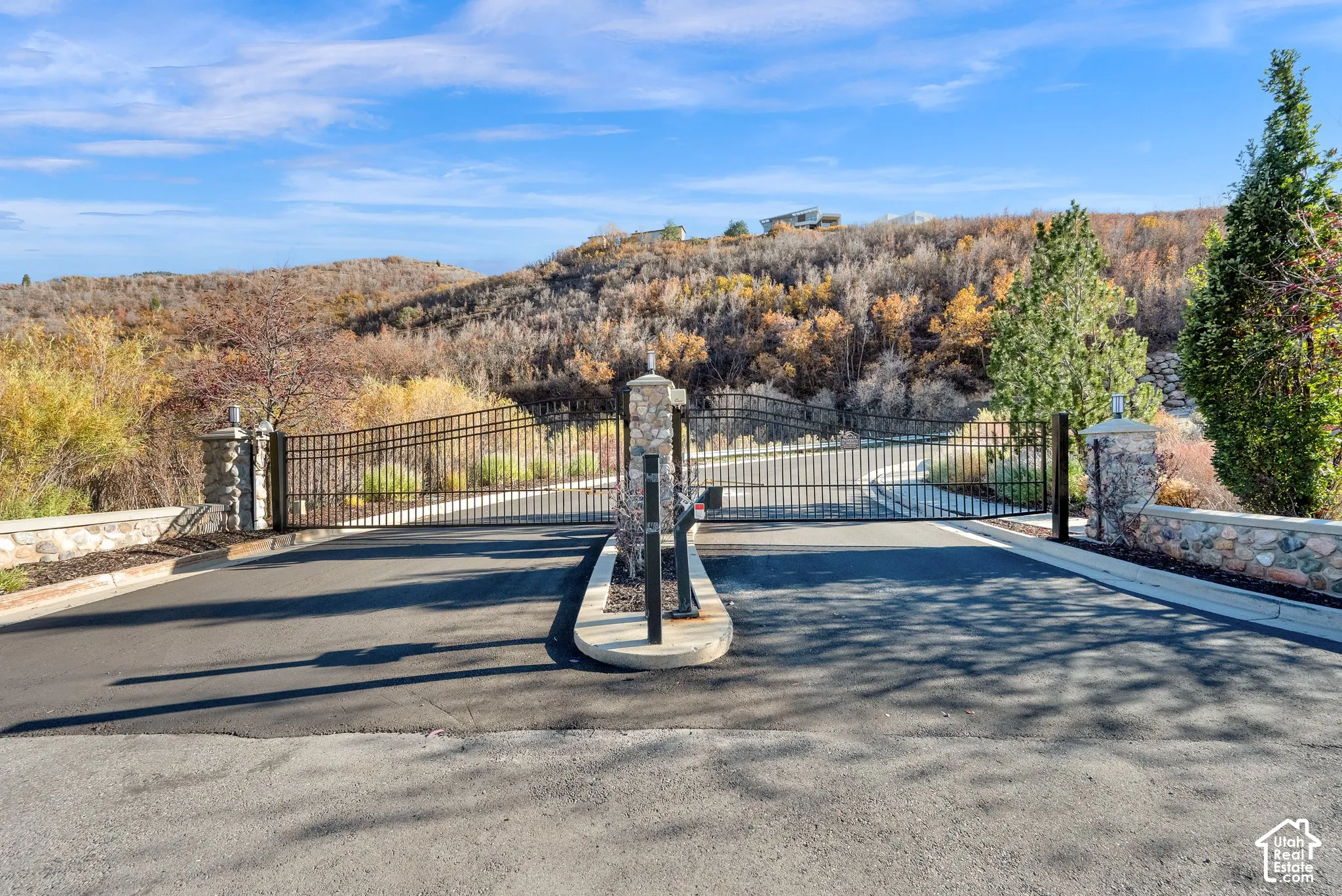 Gated entrance featuring wrought iron fencing and stone masonry pillars