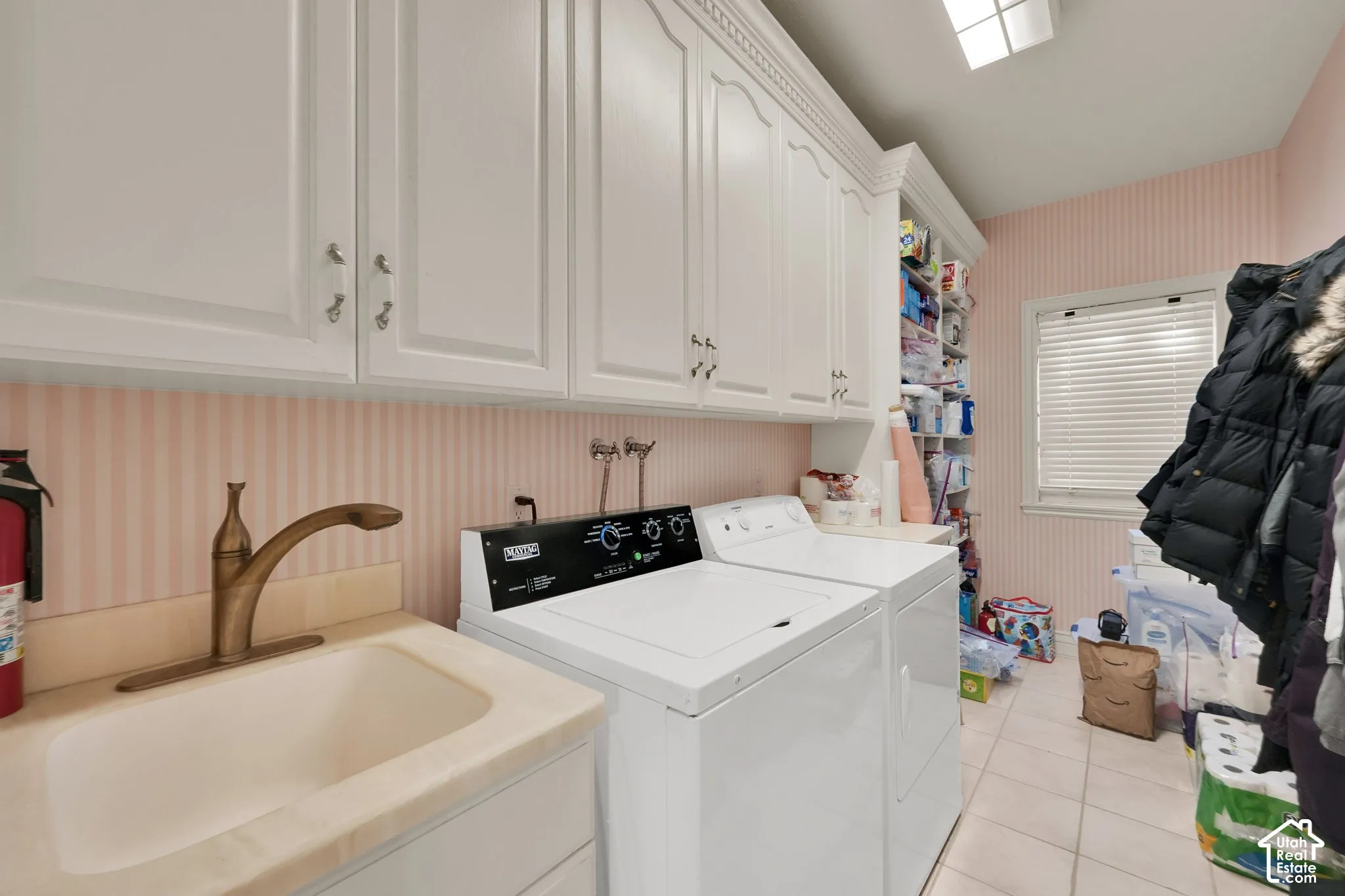 Utility space featuring white cabinetry with crown molding, a deep-basin sink with a metallic faucet, integrated shelving, and tile flooring