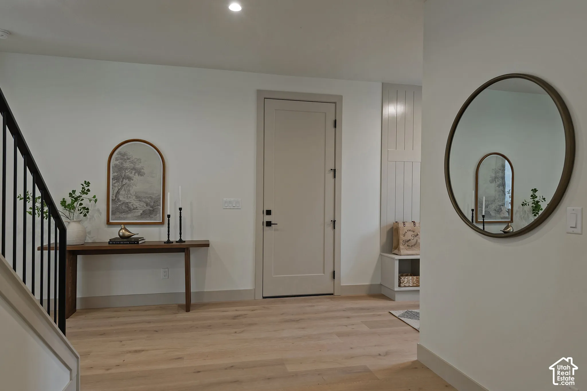 Neutral-toned entry featuring wood-finish flooring, a shaker-style interior door with matte black hardware, vertical shiplap wall accents, and an integrated built-in bench