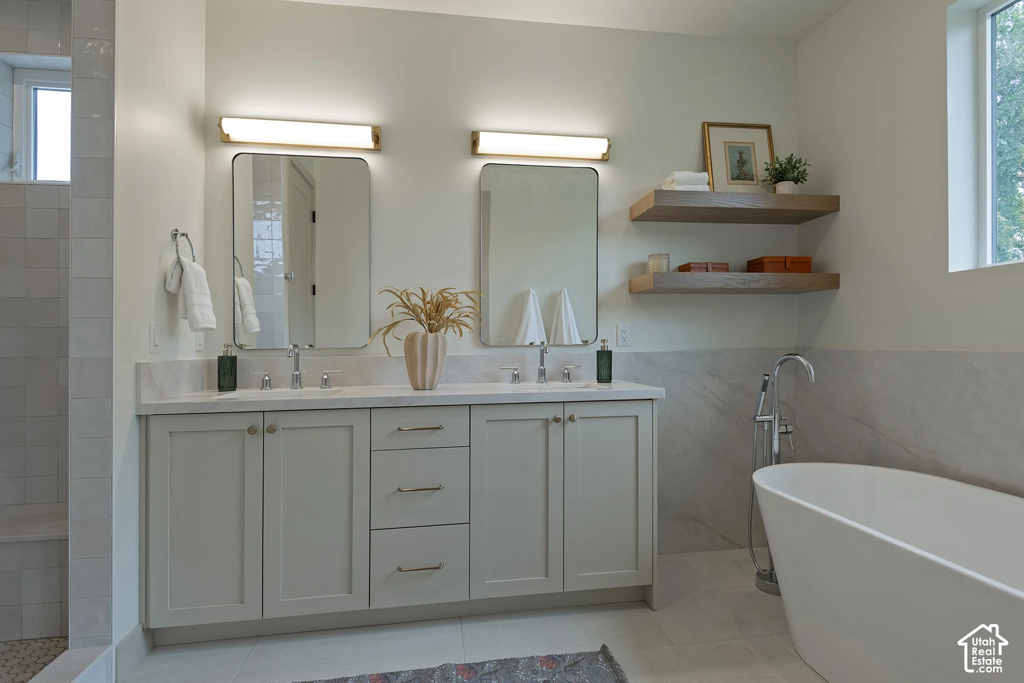 Double vanity with quartz countertop, undermount sinks, and dual rectangular mirrors, complemented by a freestanding soaking tub and built-in wood shelving