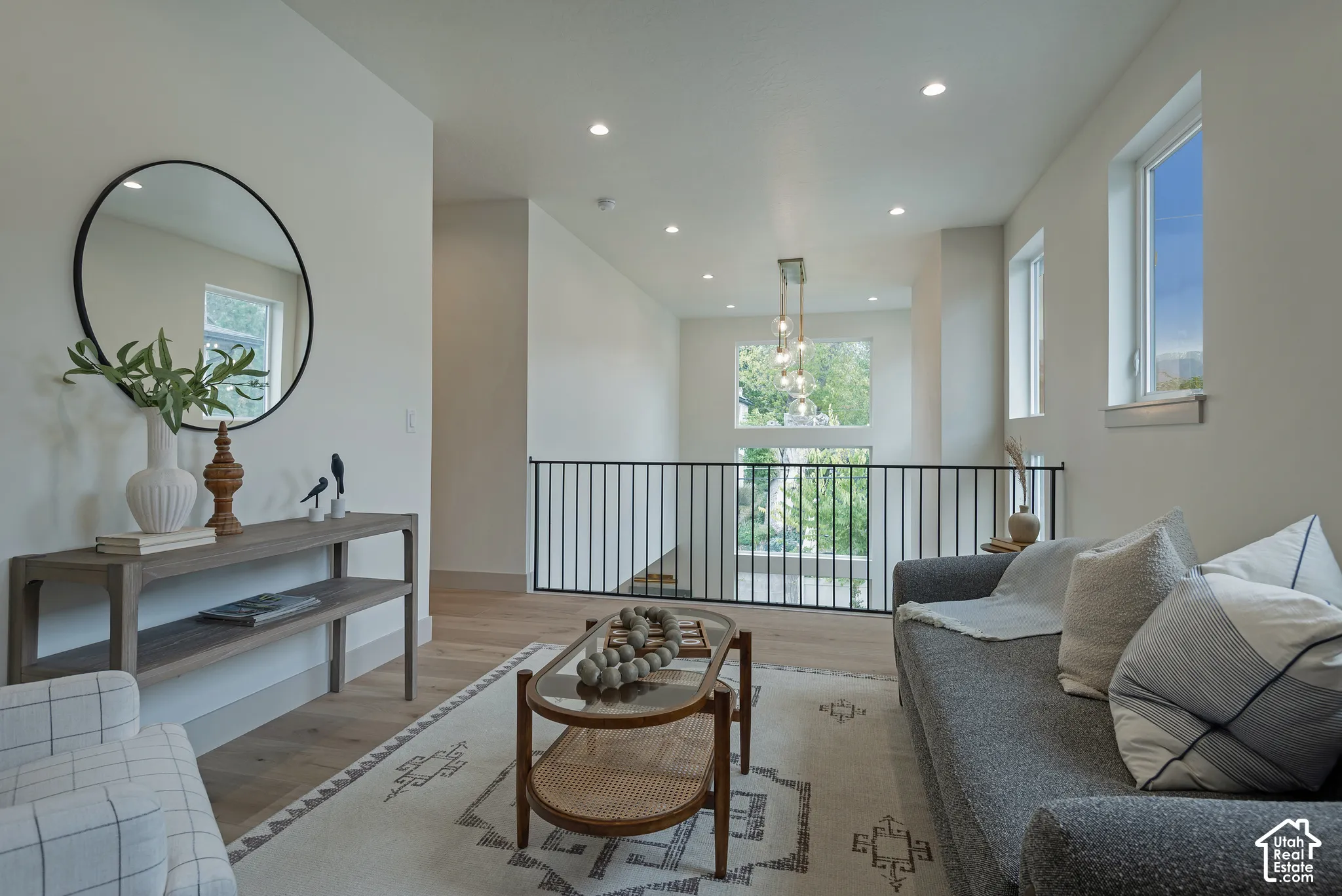 Open landing featuring wood-finish flooring, recessed lighting, double-height windows, and a metal spindle railing