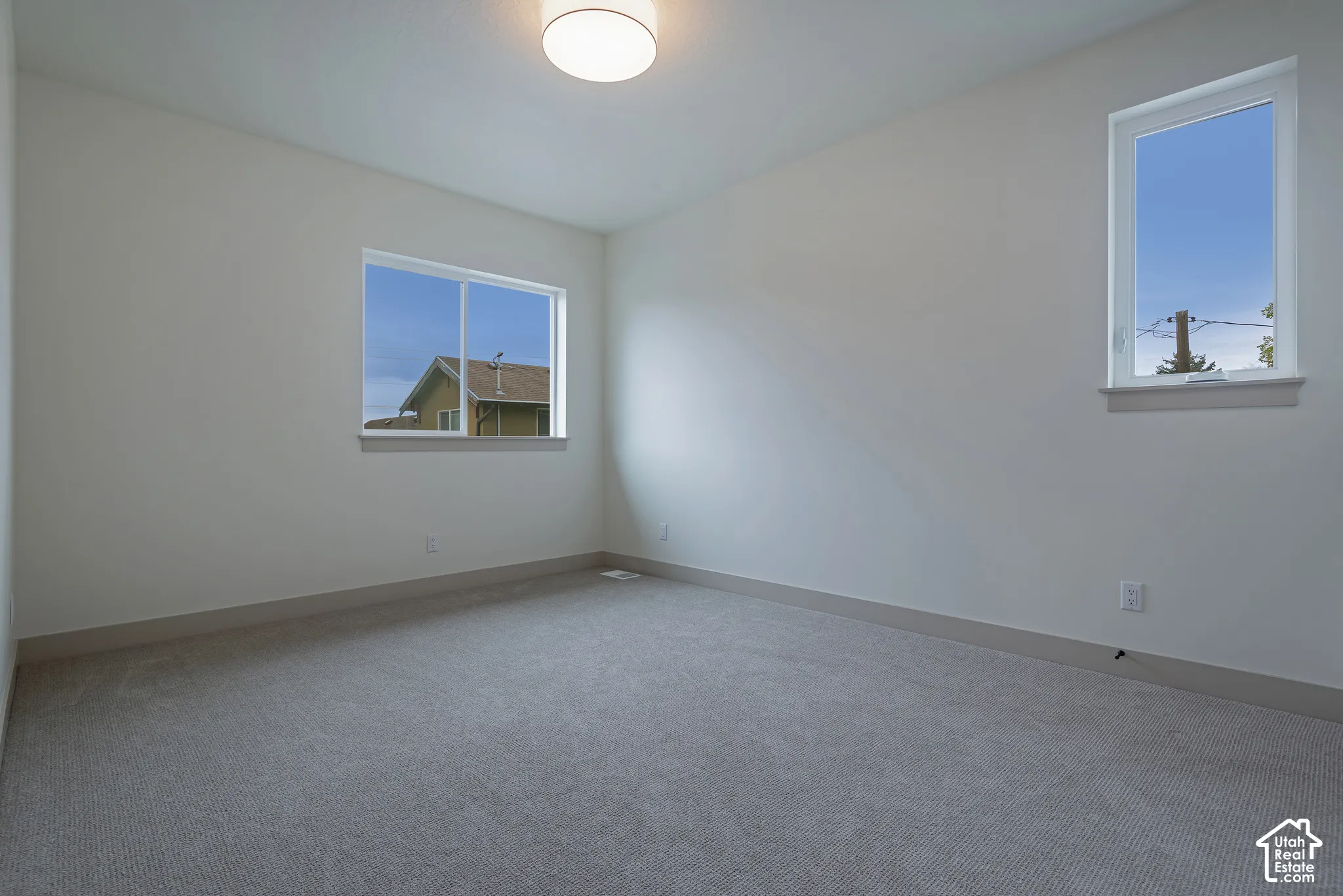 Neutral-toned interior featuring wall-to-wall carpeting, two sliding windows, and a flush-mount overhead light fixture