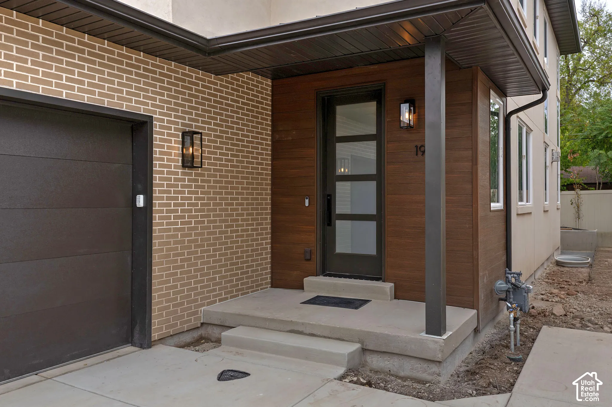 Exterior entry featuring tan brick masonry, horizontal wood-finish paneling, concrete stoop, and an insulated door with glass horizontal lites