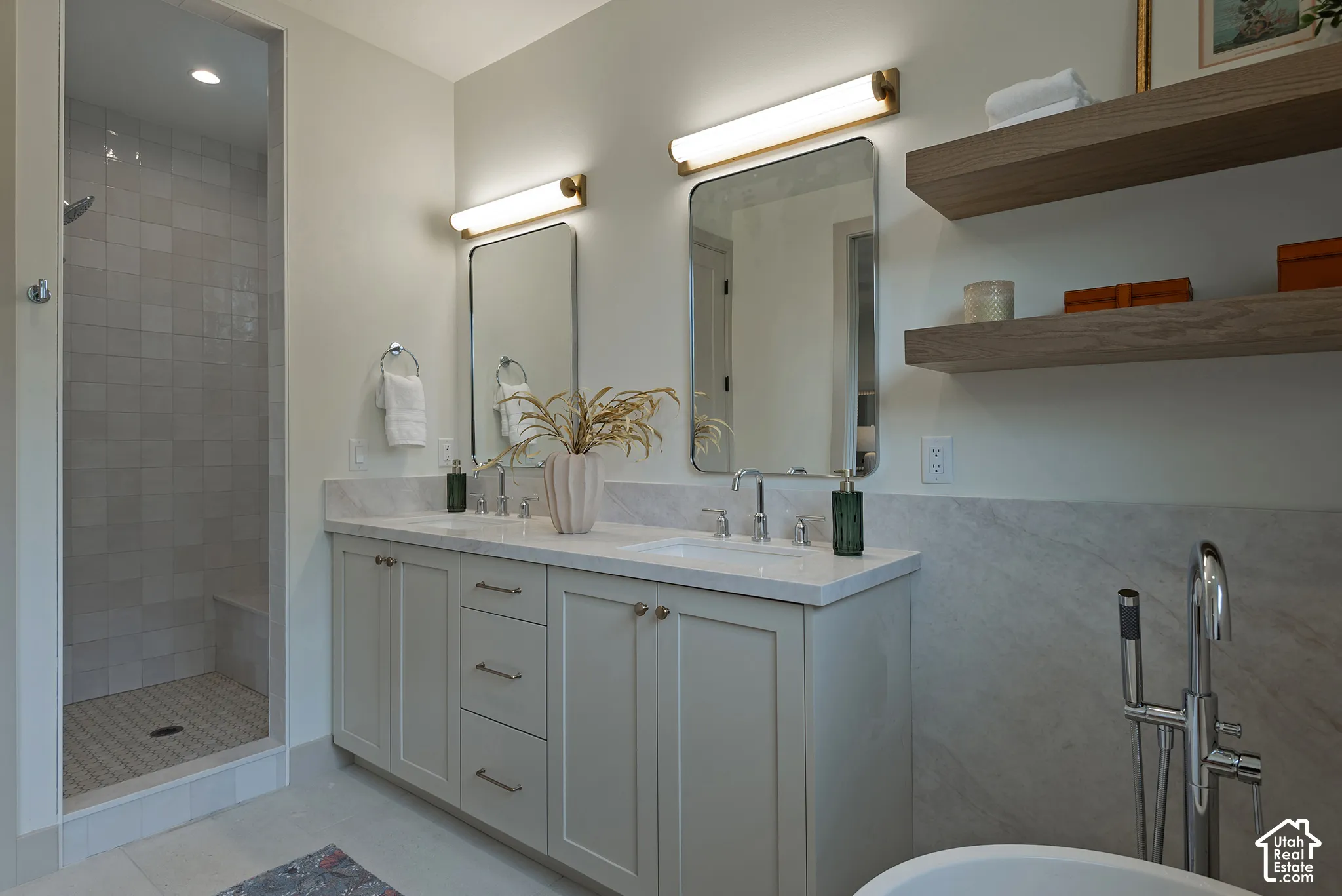 Double vanity featuring custom cabinetry with brushed hardware, stone-surface countertop, rectangular undermount sinks, and wall-mounted tubular lighting