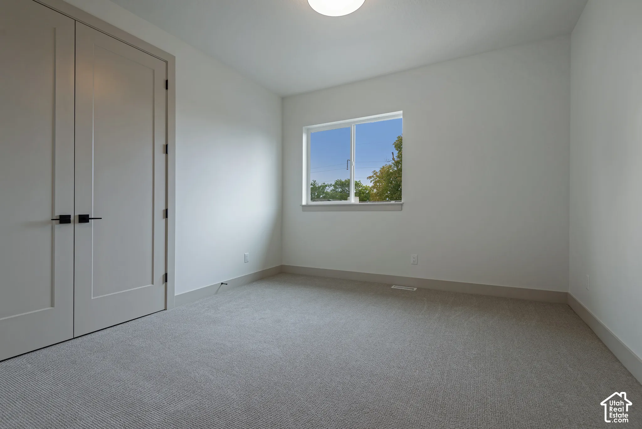 Room featuring neutral wall-to-wall carpeting, double doors with matte black hardware, and a sliding window