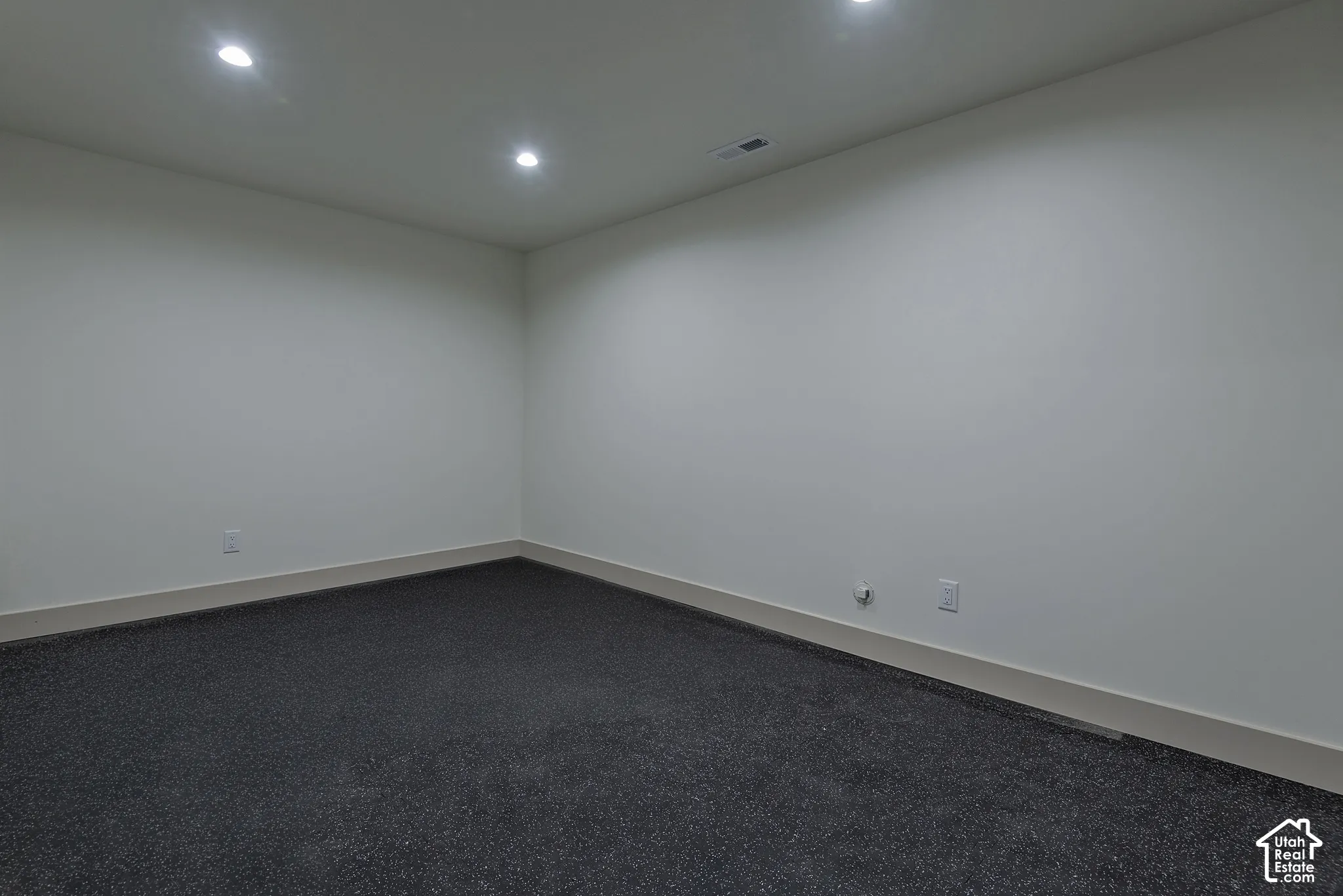Interior space featuring neutral wall tones, dark carpeting, and recessed ceiling lighting