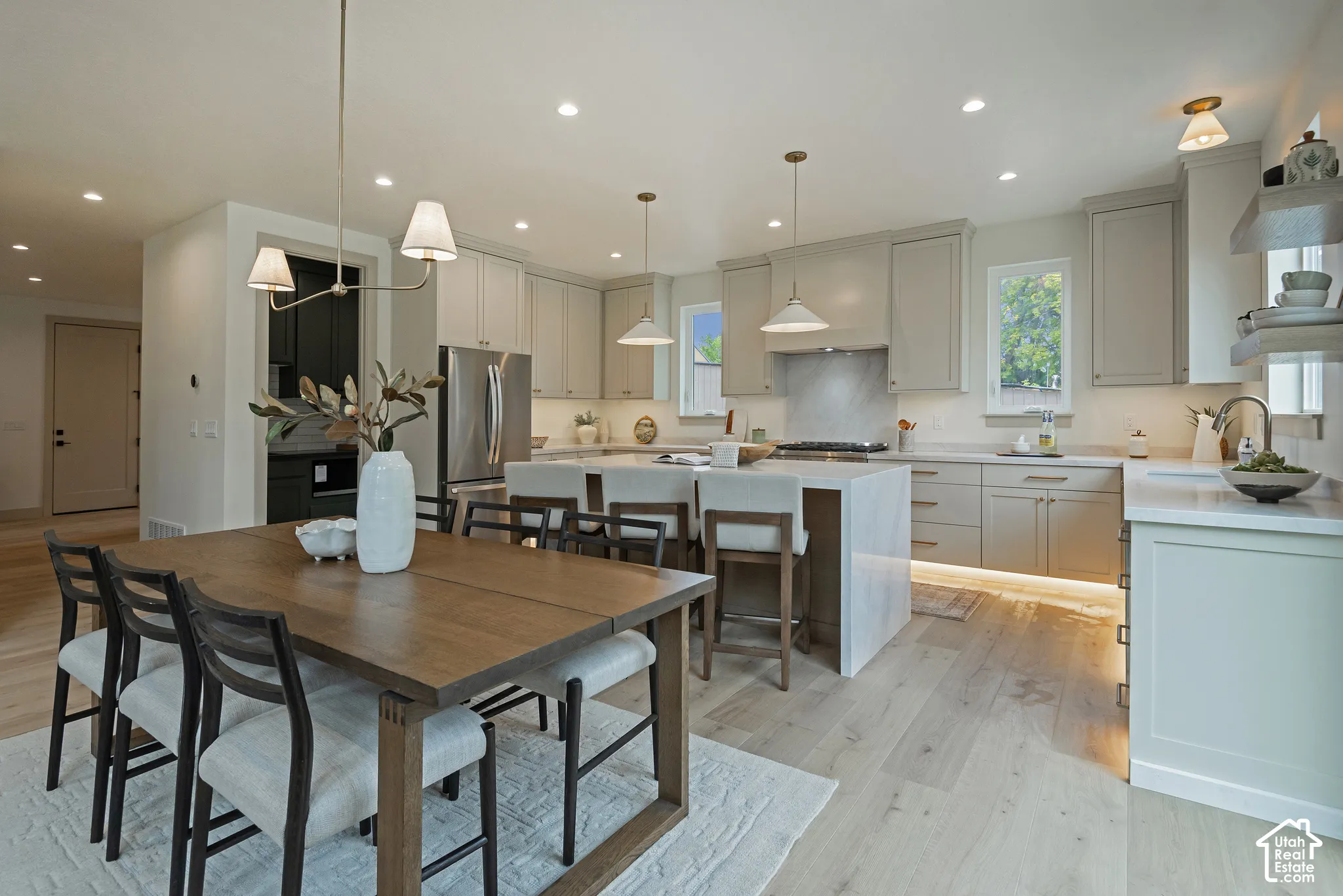 Kitchen featuring light-toned shaker cabinetry, a waterfall-edge central island, wood-finish flooring, recessed lighting, and stainless-steel appliances