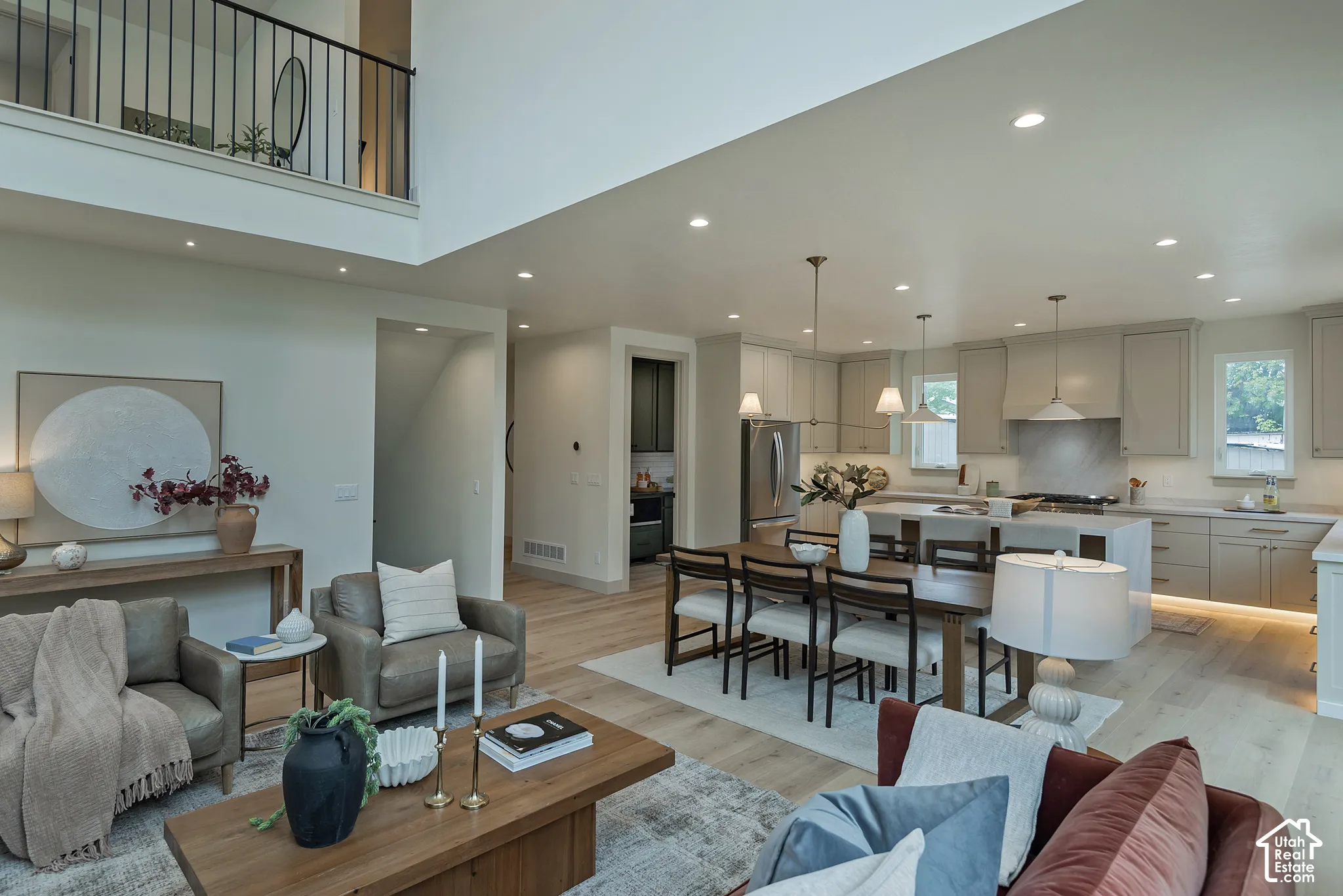 Open-concept interior featuring double-height ceilings, wood-finish flooring, recessed lighting, and a kitchen equipped with a central island and custom cabinetry