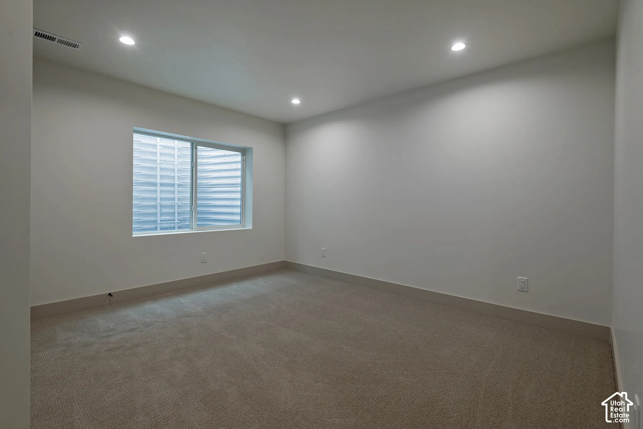 Neutral interior space featuring recessed ceiling lighting, wall-to-wall carpeting, and an egress window