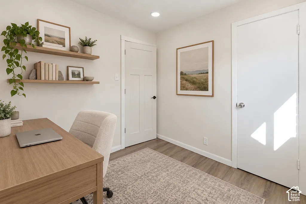 Interior room featuring wood-finish flooring, two wall-mounted floating wood shelves, and two white shaker-style interior doors with matte black hardware and a silver-toned knob