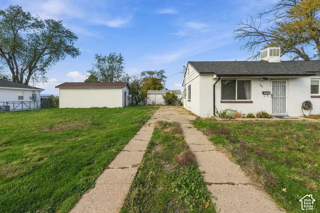 Exterior featuring painted brick siding, asphalt shingle roof, detached garage, and a concrete driveway