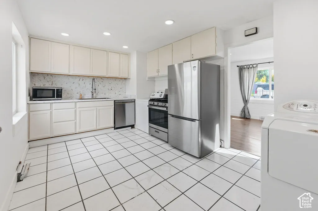 Kitchen featuring cabinetry with matte finish, stainless steel appliances, ceramic tile flooring, and recessed lighting