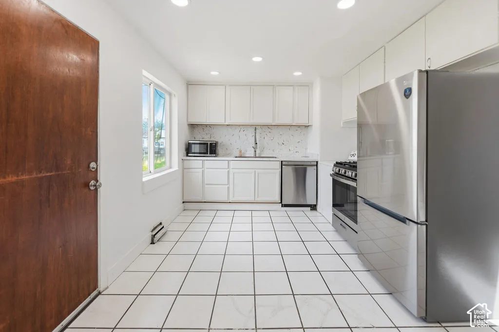 Kitchen featuring white cabinetry, stainless steel appliances, ceramic tile flooring, and recessed lighting