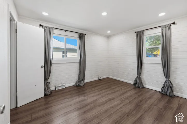 Wood-finish flooring, white painted masonry walls, and recessed lighting