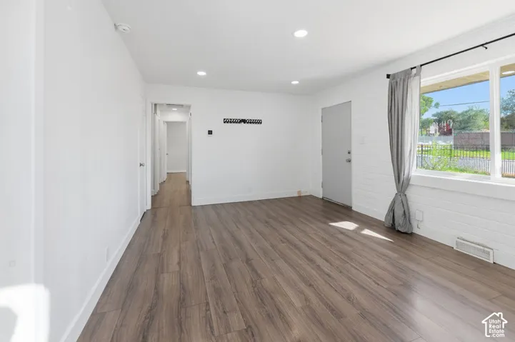 Interior space featuring wood-finish flooring, recessed lighting, and a large window with painted brick wall detailing