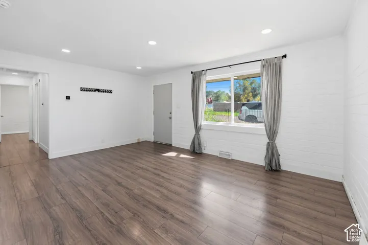Interior space featuring wood-finish flooring, white painted horizontal paneled walls, and recessed ceiling lighting