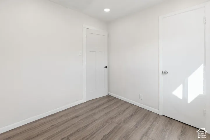 Room featuring neutral wall paint, wood-finish flooring, recessed lighting, and two interior doors with hardware