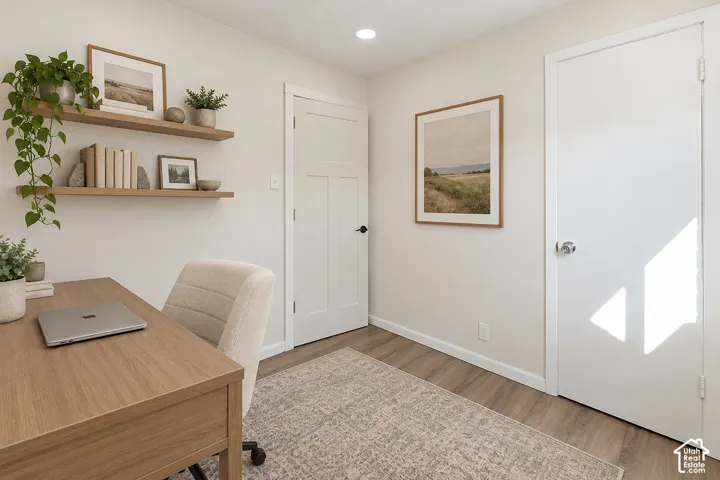 Interior room featuring wood-finish flooring, two wall-mounted floating wood shelves, and two white shaker-style interior doors with matte black hardware and a silver-toned knob