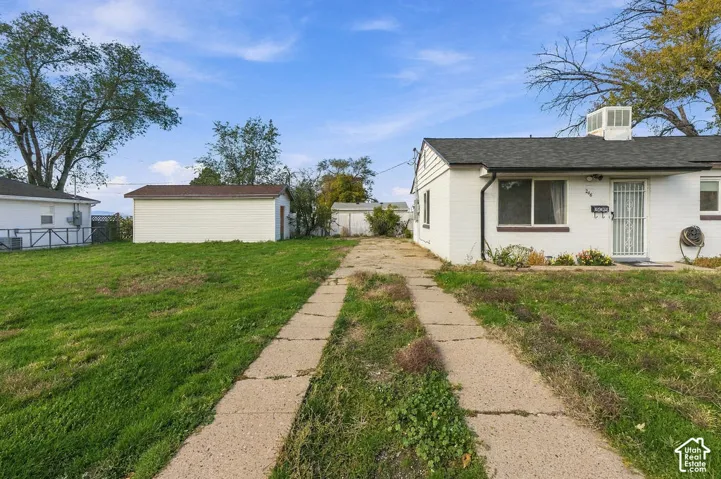 Exterior featuring painted brick siding, asphalt shingle roof, detached garage, and a concrete driveway