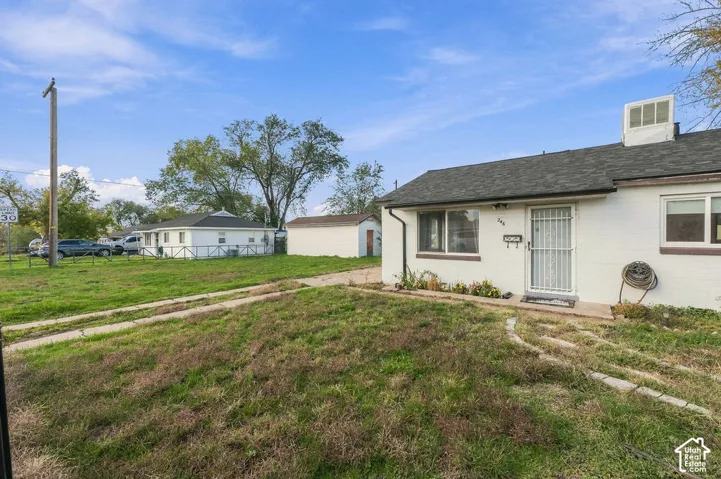 Single-story residence featuring a painted masonry exterior, composition shingle roof, integrated metal security door, and detached auxiliary structure