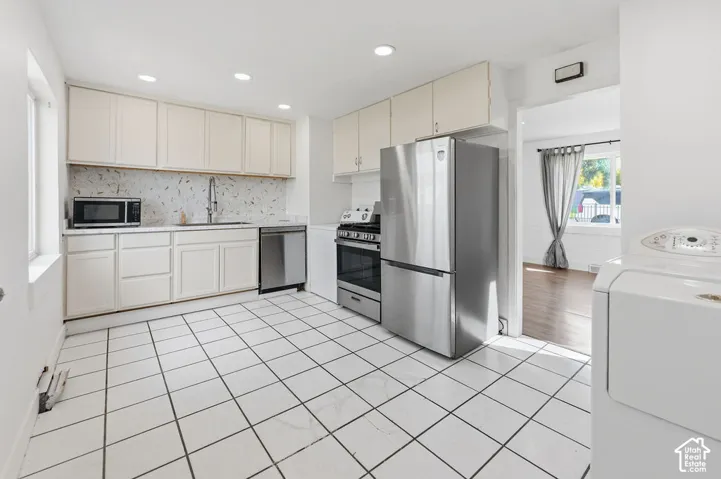 Kitchen featuring cabinetry with matte finish, stainless steel appliances, ceramic tile flooring, and recessed lighting