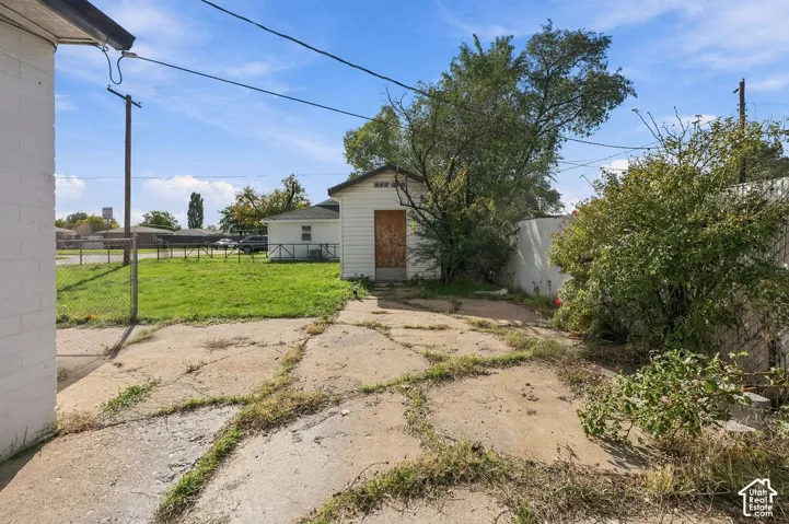 Exterior area featuring a detached outbuilding, chain-link fencing, and a concrete pad