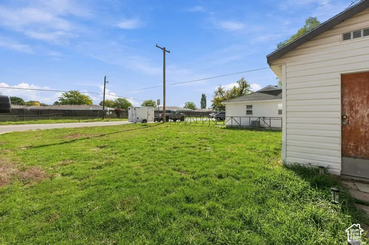 Exterior featuring light-colored horizontal siding, a side entry door, and a grass lot