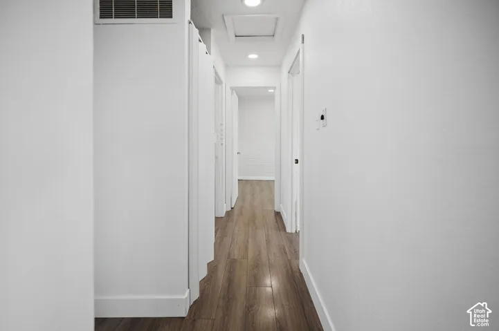 Hallway featuring wood-finish flooring, recessed lighting, and crisp white wall finishes