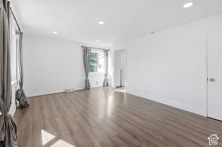 Interior space featuring white-painted brick walls, wood-finish flooring, and recessed ceiling lighting