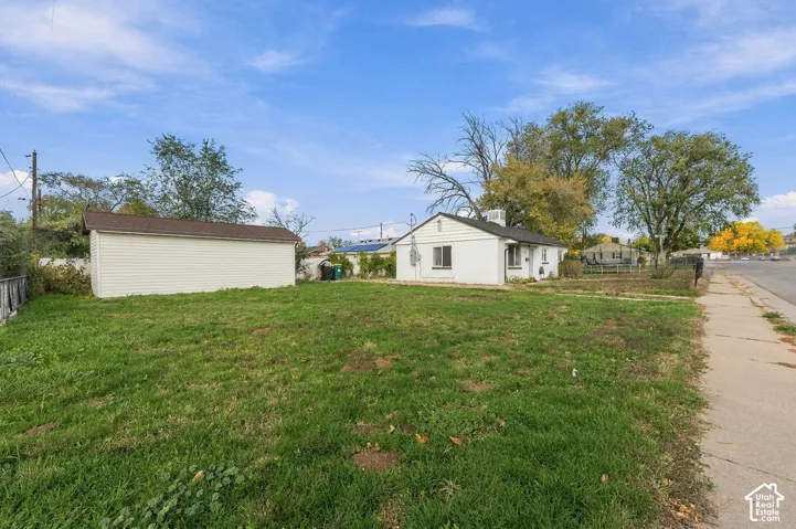 Exterior featuring a detached garage, white siding, and a spacious grass yard
