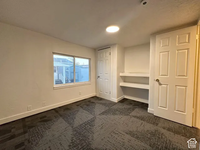 Interior room featuring patterned carpeting, recessed shelving, six-panel doors, and a sliding window