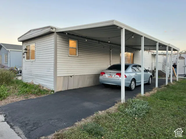Exterior featuring horizontal metal siding, a paved driveway, and an attached metal-frame carport