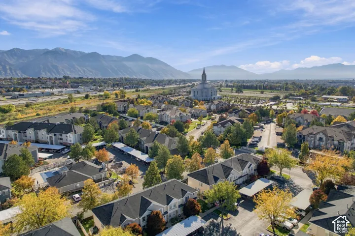 Aerial perspective of a multi-unit residential community featuring asphalt-shingled rooflines, covered parking structures, mature trees, and a mountain backdrop