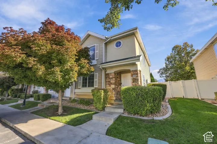 Two-story exterior featuring stone veneer accents, lap siding, a circular accent window, a covered entryway, and a vinyl privacy fence