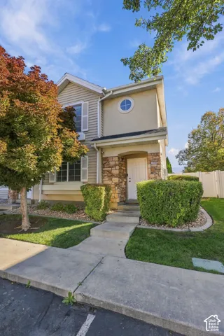 Two-story exterior featuring stone veneer accents, horizontal siding, a circular accent window, and a covered entryway