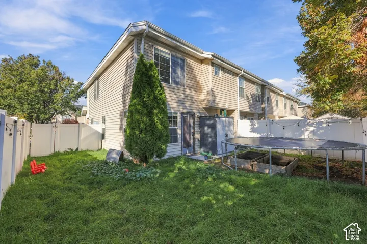 Two-story exterior featuring light-toned horizontal siding, dual-pane windows, and a fully enclosed private yard with vinyl fencing