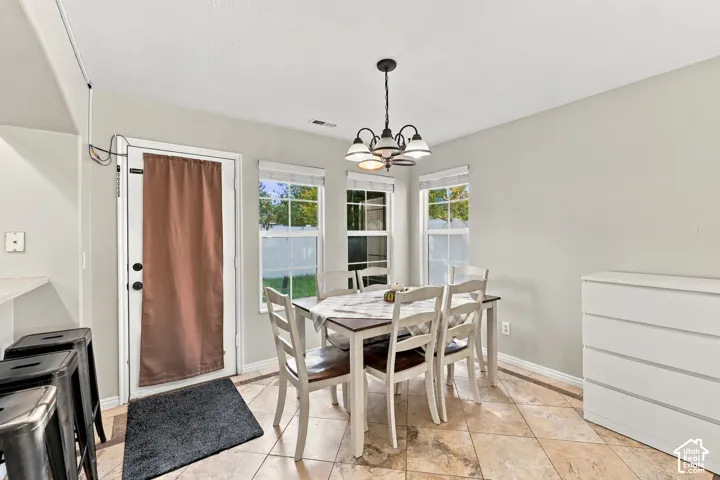 Neutral-toned interior featuring diagonal-set ceramic tile flooring, three large windows with muntin detailing, and a multi-arm metal chandelier