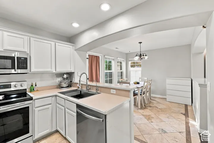 Kitchen featuring white shaker-style cabinetry, stainless steel appliances, a high-arc faucet, and tiled flooring