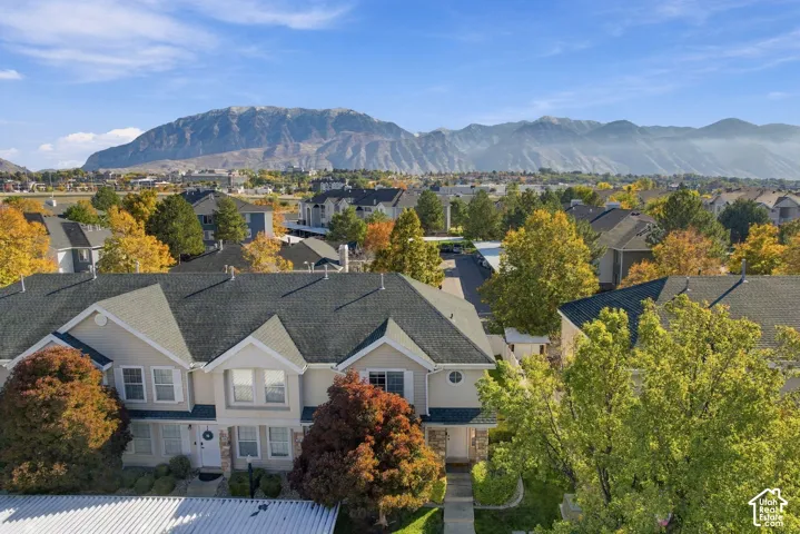 Multi-family residential structure featuring a shingled roof, light-toned siding, stone veneer accents, and mountain range scenery