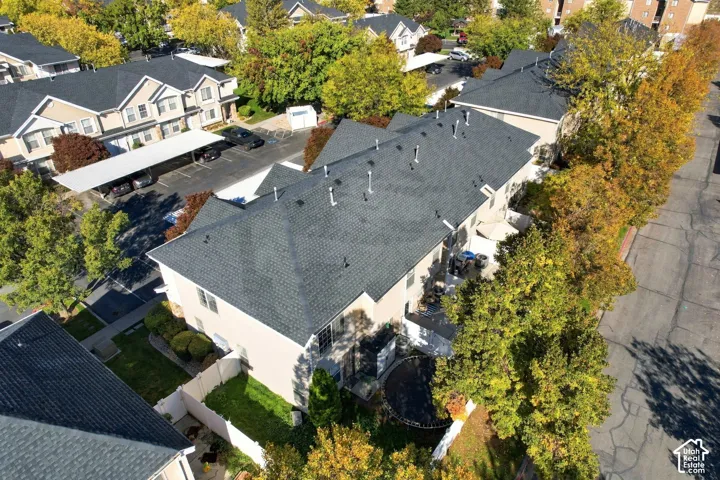 Multi-story residential building featuring a dark shingle roof, stucco exterior, assigned carport parking, and fenced perimeter
