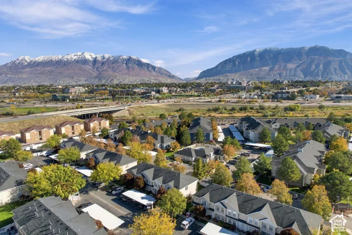 Aerial perspective of a multi-unit residential community featuring covered parking structures, mature trees, and expansive mountain scenery