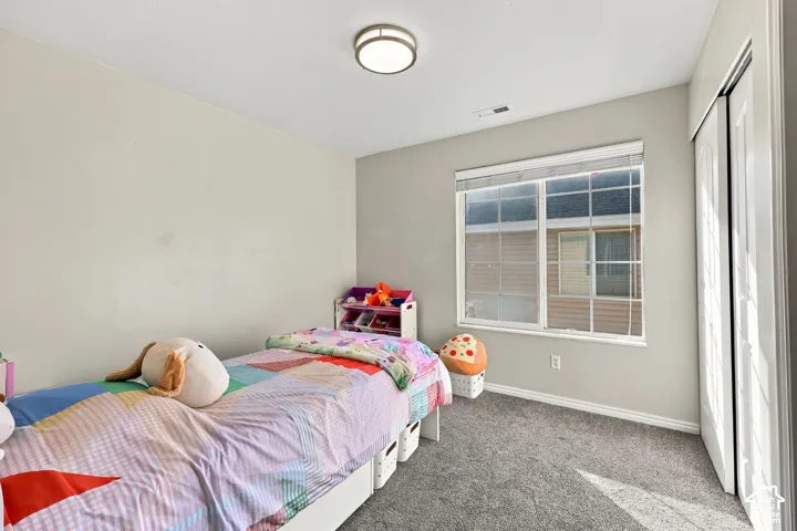 Room featuring neutral wall paint, carpeted flooring, a grid-pattern window with integrated blinds, and a built-in closet with sliding doors