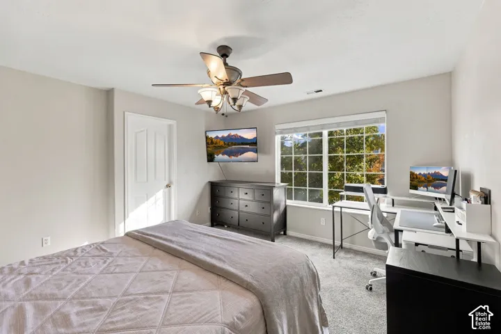 Neutral-toned room featuring neutral wall-to-wall carpeting, a multi-light ceiling fan with integrated blades, a grid-pattern window, and a multi-panel interior door