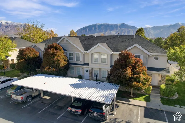 Multi-family exterior featuring horizontal siding, stone veneer accents, a pitched shingle roof, a dedicated metal carport structure, and a prominent mountain backdrop