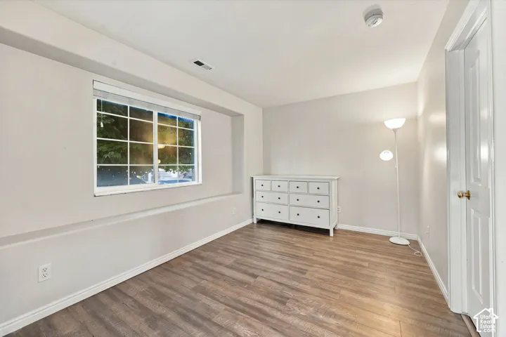 Room featuring wood-finish flooring, a recessed window nook with a multi-pane slider, and a solid-core interior door