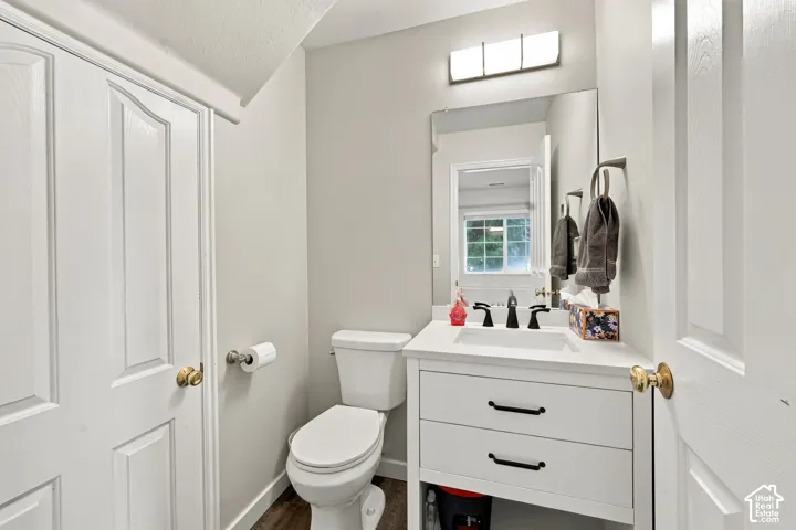 White vanity with two drawers, integrated rectangular sink, stone-finish countertop, matte black faucet, and modern three-light wall-mounted fixture