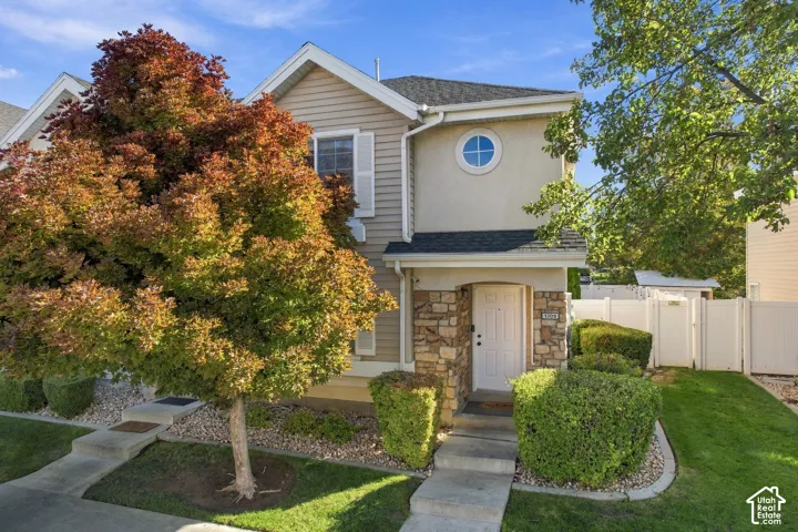 Multi-level exterior featuring a stone veneer entryway, horizontal siding, decorative circular accent window, and concrete walkway